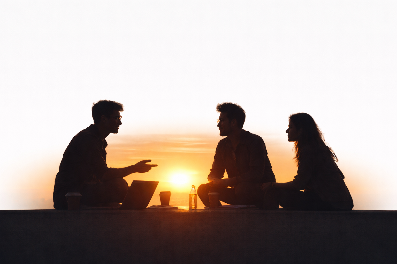 Silhouettes of people engaged in a thoughtful business discussion during sunset, representing founder conversations, ideas, and strategic thinking.
